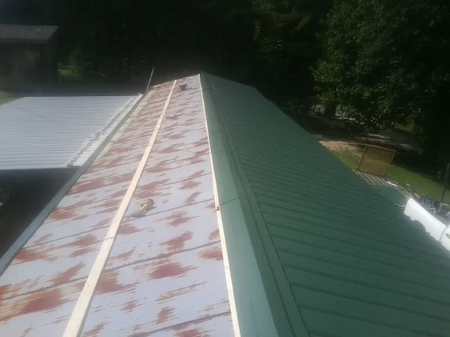 Old rusted panels beside newly installed green metal roofing — Wind Damage Roof Repair by Roofing Brothers in Ann Arbor