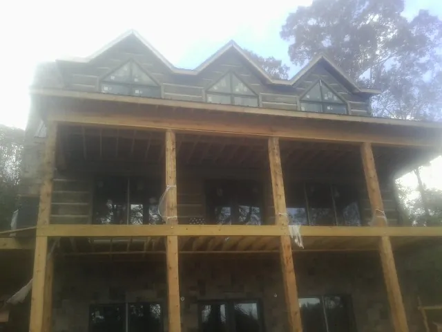 Dormers and porch framing on a large log home under construction — Roof Coating work by our crew in Ann Arbor