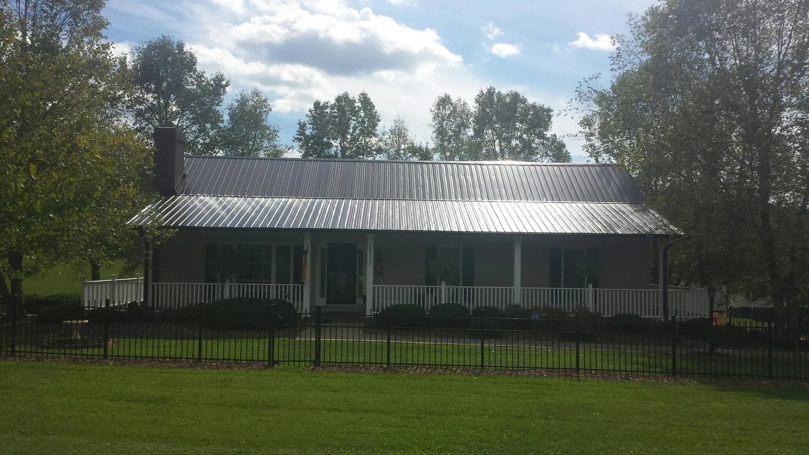 Gray metal roof on a brick ranch with a full width front porch — Gutter Guard Installation work by our crew in Ann Arbor