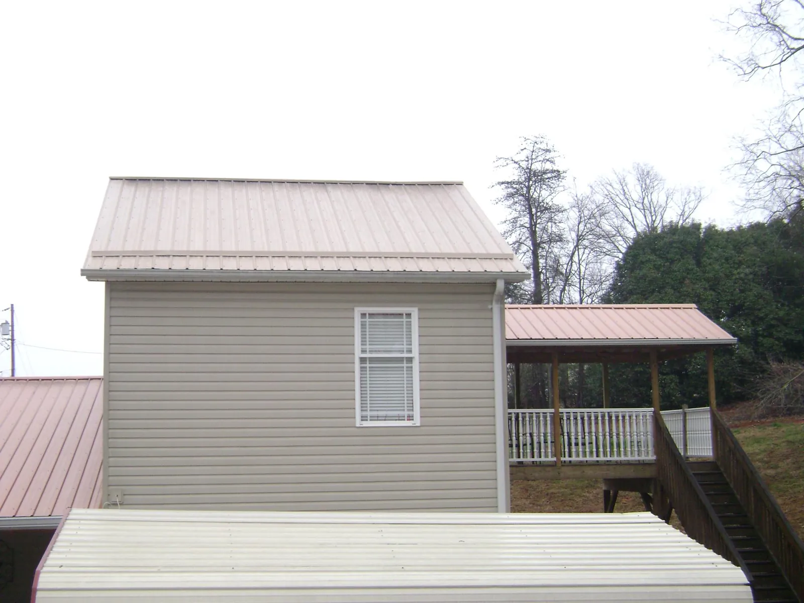 Tan metal roofs on a two story addition and attached porch, from a Roof Replacement job in Ann Arbor