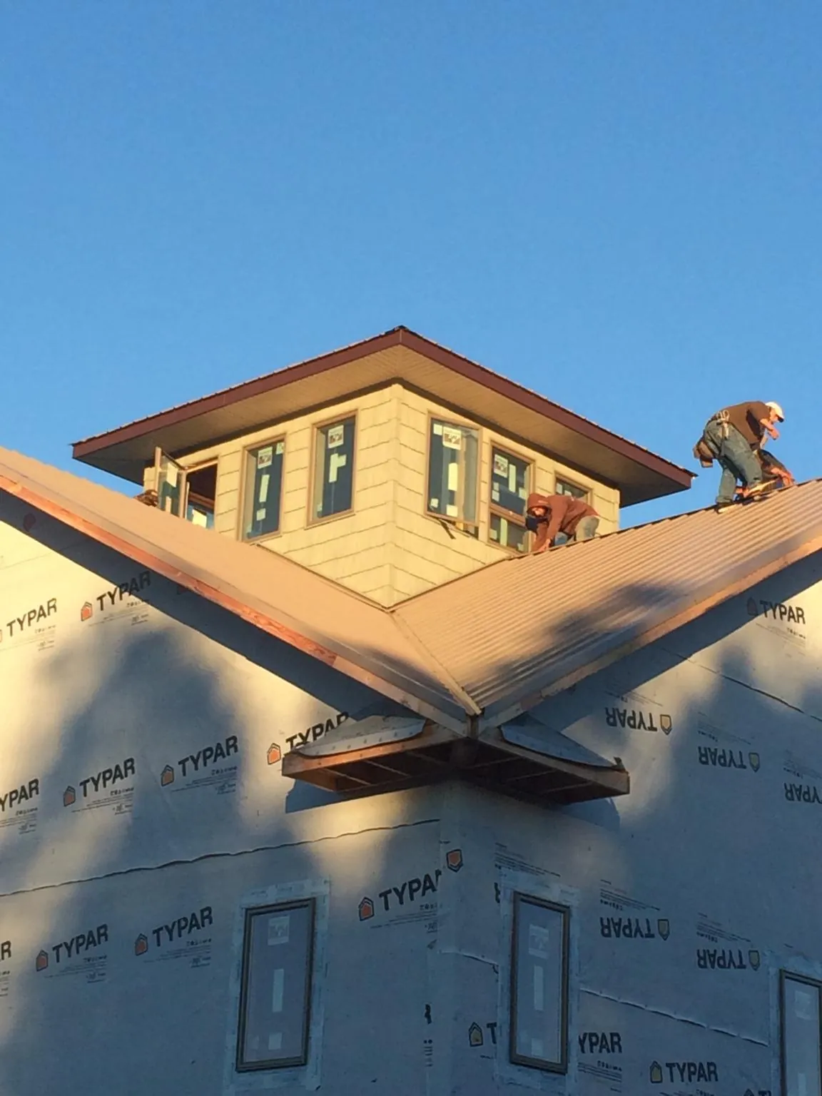 Roofers working around a rooftop cupola on a new metal roof at sunset — Roof Waterproofing in Ann Arbor by Roofing Brothers